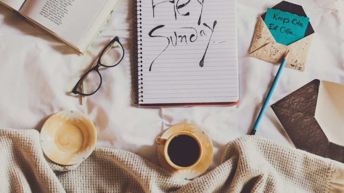 white ceramic mug on white notebook beside blue pen