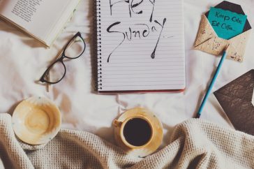 white ceramic mug on white notebook beside blue pen