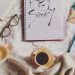 white ceramic mug on white notebook beside blue pen